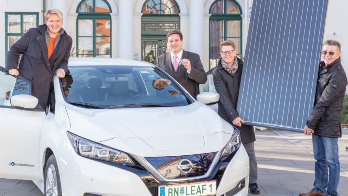 Vizebürgermeisterin Dr. Helga Krismer und Bürgermeister Dipl.-Ing. Stefan Szirucsek stehen neben ein e-Auto, Dr. Gerfried Koch und Werner Czaker halten gemeinsam ein Photovoltaik-Modul hoch.