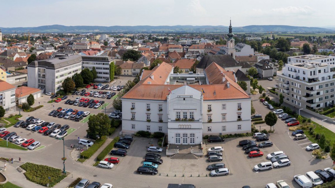 Hier sieht man das Rathaus von vorne, also aus Sicht des Klostergartens. Wo die flexible und begrünte Nutzungszone, der Klostergarten, die Esplanada und Aupromenade geplant sind, stehen noch großflächige, asphaltierte Parkplätze.