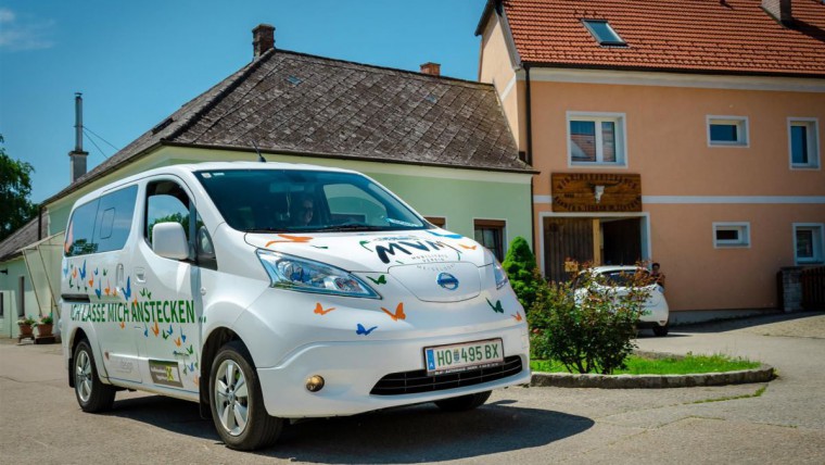 Ein weißer Kastenwagen mit bunten Schmetterlingsmotiven und dem Text "ich lasse mich anstecken" ist abgebildet.